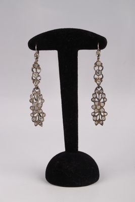 a pair of earrings on a black stand with a white background
