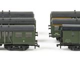 two green train cars sitting side by side on a white surface