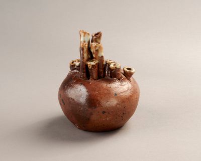 un petit vase marron contenant un bouquet de petites choses