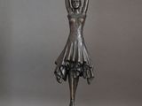 statue en bronze représentant une femme tenant une raquette de tennis dans une main et une balle de tennis dans l'autre