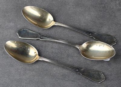 trois cuillères en argent et deux cuillères en argent posées sur une table