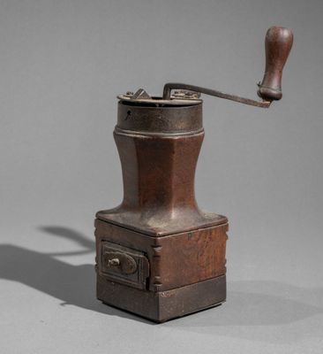 an old coffee grinder with a wooden handle on a gray surface