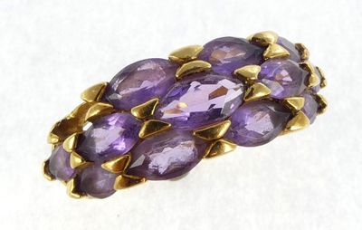 a close up of a ring with purple stones on a white surface