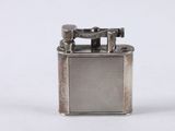 an old silver lighter with a metal cover on a white surface