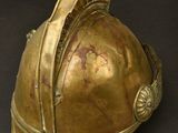 brass fire helmet on a black surface with a black background