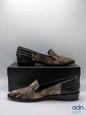 a pair of brown snakeskin slippers sitting on top of a black box