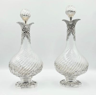 une paire de vases anciens en cristal taillé, posés sur des socles, sur fond blanc