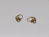 une paire de boucles d'oreilles en or sur une surface blanche