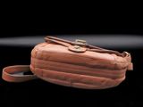 brown leather fanny bag on a black surface with a black background