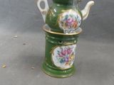 a green tea pot with a lid and a flower design on it