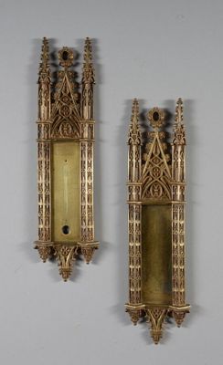 deux appliques murales dorées sur un mur blanc