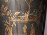 a black vase with a painting on it sitting on a table