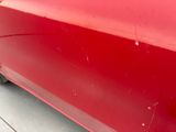 a close up of a red car with scratches on the side of it