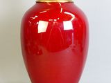 a red vase with a gold lid sitting on a table