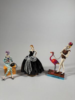 trois figurines représentant des personnes en costume tenant des flamants roses
