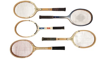 four tennis rackets are lined up on a white surface