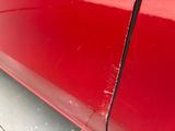 a close up of a red car with scratches on the side