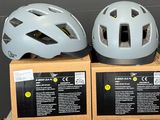 trois casques de vélo posés sur une boîte en carton, elle-même posée sur une table