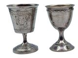 two silver goblets sitting next to each other on a white surface