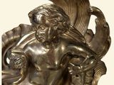 a silver statue of a man and a woman on a wave