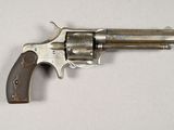un vieux revolver avec une poignée en bois sur une surface blanche