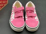 pink and white checkerboard vans slip - ons on a black surface