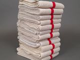 une pile de serviettes blanches et rouges posée sur une surface grise