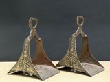 pair of antique brass bells on wooden stand with black background