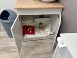 a white cabinet with a wooden top and a trash can