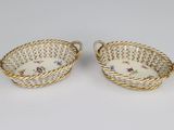 a pair of porcelain baskets with floral designs on them