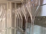many empty wine glasses lined up on a glass shelf