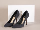 une paire de chaussures noires à talons hauts posée devant une boîte blanche