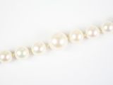 un gros plan sur un collier de perles blanches posé sur une surface blanche