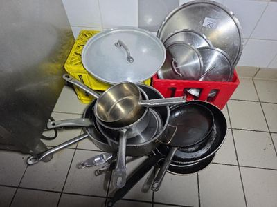 de nombreuses casseroles et poêles posées par terre dans la cuisine