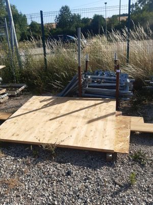 une plate-forme en bois posée à même le sol, près d'une clôture