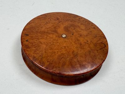 a round wooden box with a button on top of it