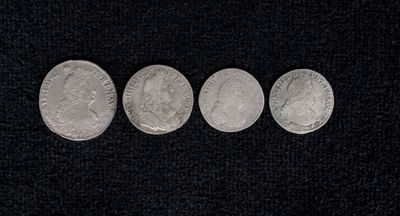four silver coins are arranged in a row on a black surface