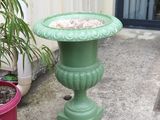 a birdbath sitting on a green pedestal next to a potted plant