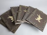 five brown books with gold designs are stacked on top of each other