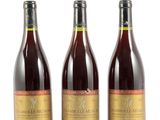trois bouteilles de vin posées les unes à côté des autres sur une surface blanche
