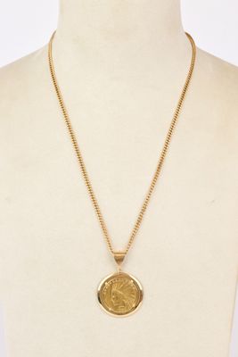 a gold necklace with a coin on a mannequin neck