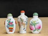 three chinese porcelain snuff bottles sitting on top of a wooden table