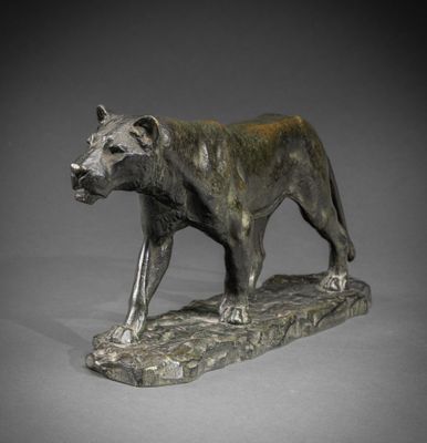 statue en bronze représentant un lion perché sur un rocher, sur fond gris