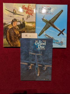 trois livres sont posés sur une nappe rouge, sur une table
