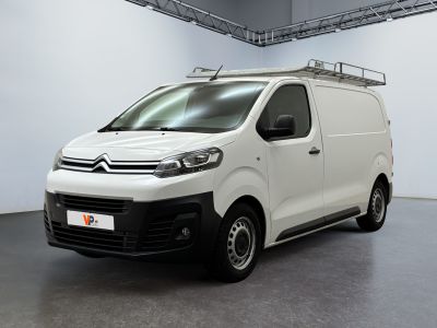 La camionnette blanche est garée dans une grande pièce équipée d'une galerie de toit.
