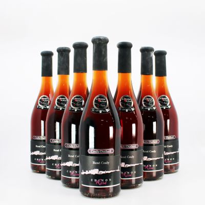 six bottles of wine are lined up in a row on a white surface