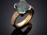 a close up of a ring with a green stone surrounded by diamonds