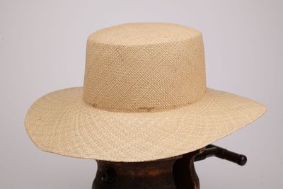 une photo d'un chapeau de paille posé sur un support en bois