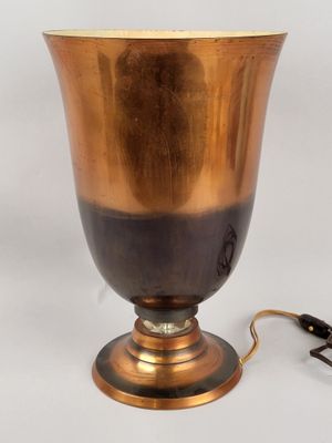 un vase doré avec une anse noire sur fond blanc