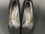 a pair of black sued shoes on a gray surface